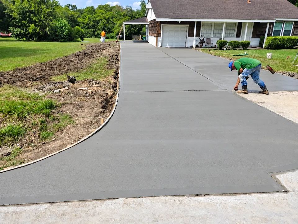 Finished concrete driveway leading to a house with a garage