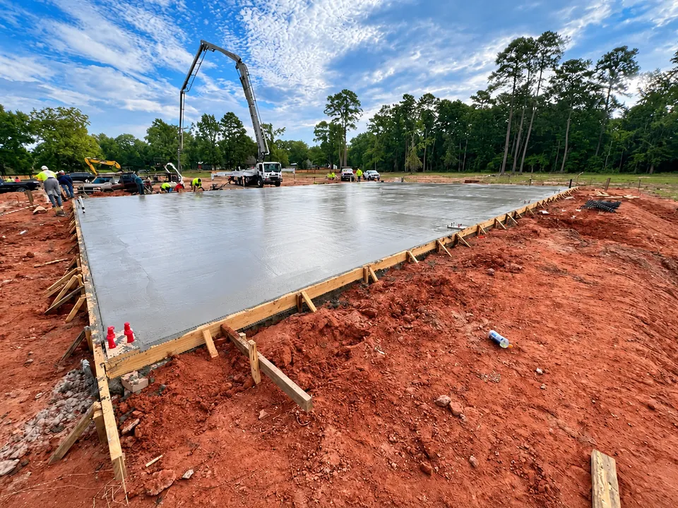 Freshly poured concrete building slab with a boom pump truck behind it